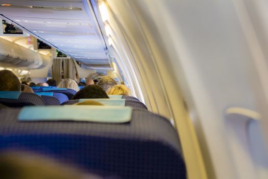 Interior of passenger airplane with people on seats.