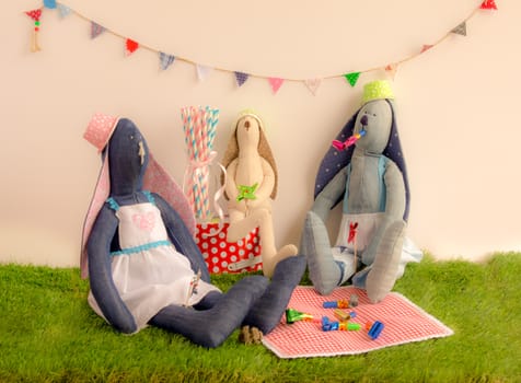 Handmade cloth rabbit dolls sitting on the grass and celebrating in party concept.