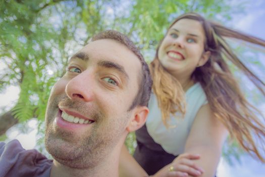 Couple doing silly and funny faces while taking selfie picture in the park.