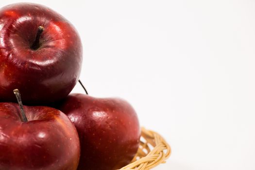 Close up of ripe red apples in wicker basket isolated on white background.