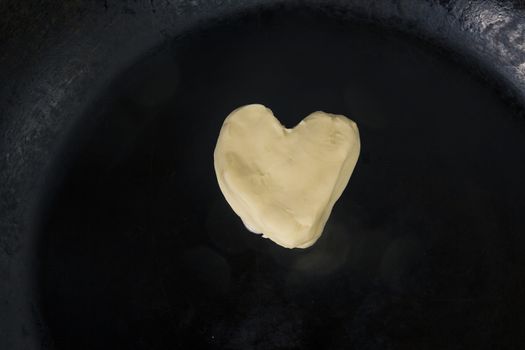 Butter in shape of heart on hot pan - Close up top view 