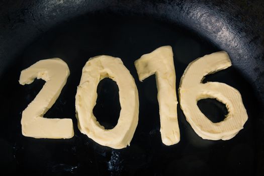 Butter in shape of number 2016 on hot pan - Close up top view 
