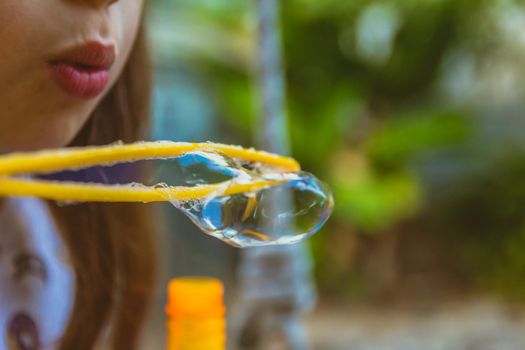 Close up of little girl blowing soap bubbles.