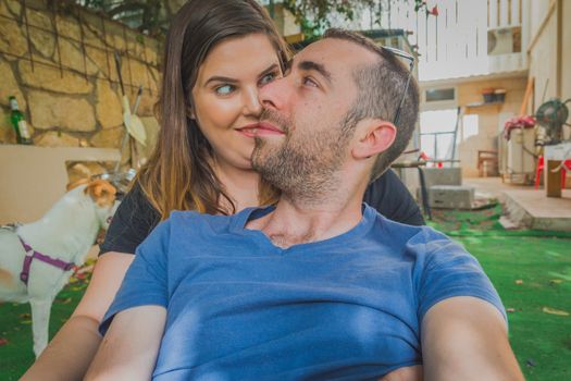 Young couple enjoying together in the backyard. They are smiling, laughing and making funny faces together.