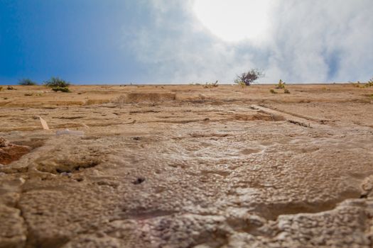 Closeup low angle view of the Western Wall in the old city of Jerusalem Israel. In the cracks between the bricks there are numerous notes with pleads and requests from people to the hebrew god.