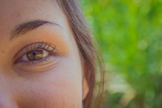 Woman's brown eye closeup in the park.