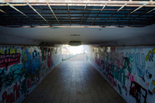 Pedestrian underpass tunnel with painted of graffiti on the walls.