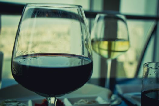 Close up on glasses with red and white wine on white table.