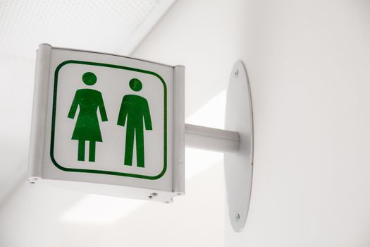 Public modern white and green restroom sign on white wall
Public modern white and green restroom sign on white wall.
