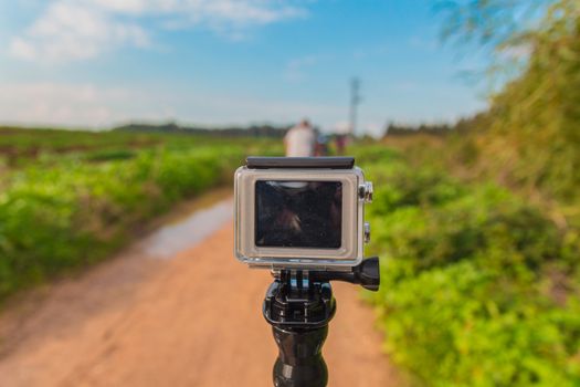 GoPro action camera on stick in dirt road at rural area.