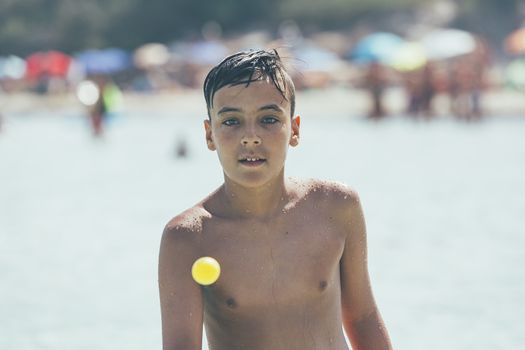 boy with green eyes playing tennis on the beach