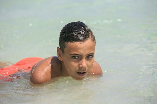 Boy with beautiful green eyes looking at the camera on the beach