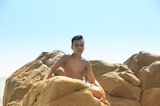 Boy with beautiful green eyes looking at the camera on the beach