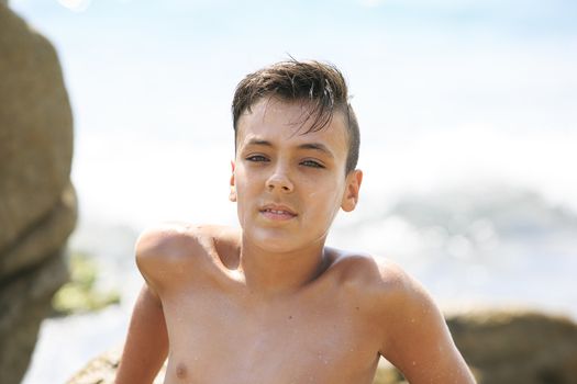 Boy with beautiful green eyes looking at the camera on the beach