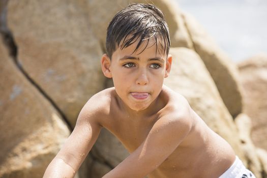 Boy with beautiful green eyes looking at the camera on the beach