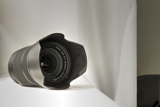 Black camera zoom lens on white cloth.