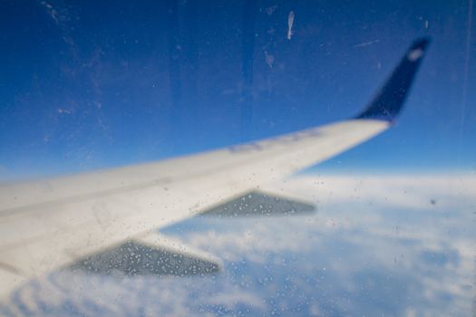 Frozen condensation of ice crystals on the window of an airplane with the wing in the back.