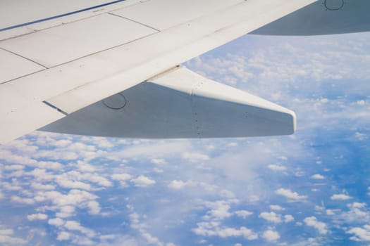Airplane wing on the sky and over sea with clouds.