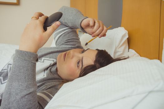 Woman applying makeup while she is lying on her bed