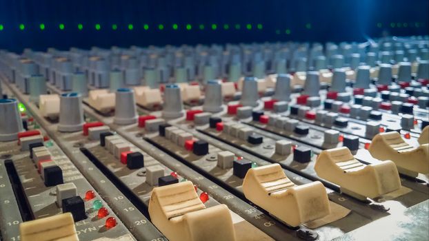 Professional audio mixing console with faders in recording studio.