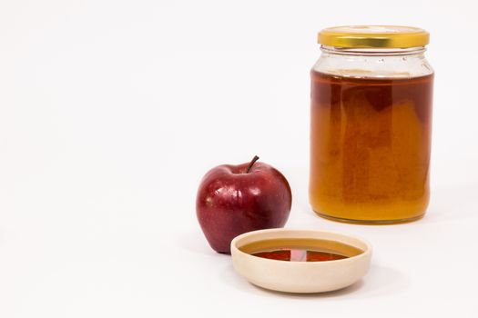 Red apple and jar of honey bowl of honey isolated on a white background. Symbols of Jewish New Year - Rosh Hashanah.