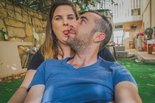 Young couple enjoying together in the backyard. They are smiling, laughing and making funny faces together.