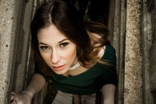 Beautiful brunette woman posing outdoor in abandoned industrial place - dark mysterious artistic portrait.