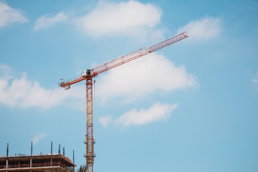 Tower crane in construction site over blue sky with clouds .