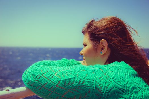 Woman leans on the railing and looking out to sea on the horizon