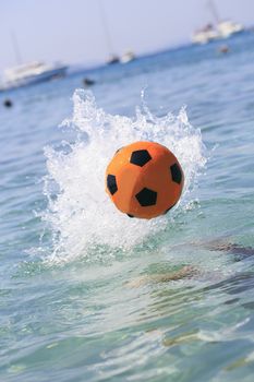 Orange soccer ball splashing on the water