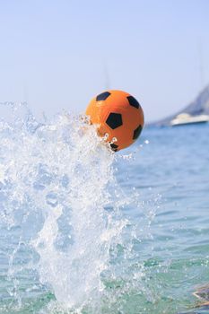 Orange soccer ball splashing on the water