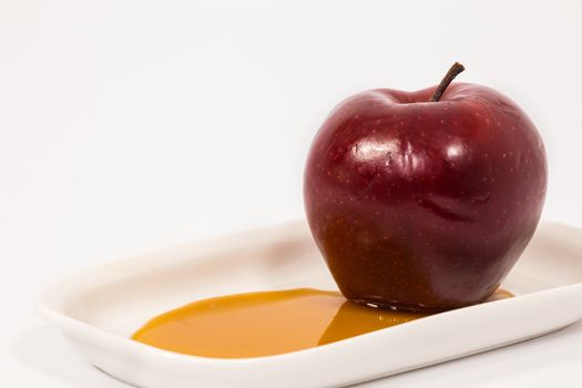 Red apple on white plate with honey isolated on a white background. Symbols of Jewish New Year - Rosh Hashanah.  