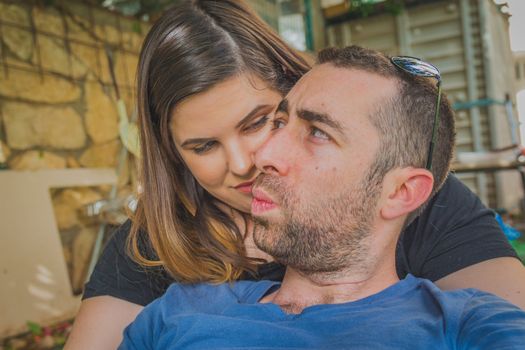 Young couple enjoying together in the backyard. They are smiling, laughing and making funny faces together.