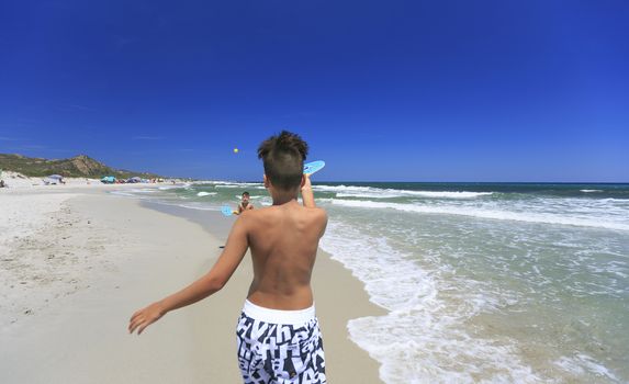 boys playing tennis on the beach