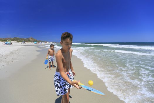 boys playing tennis on the beach