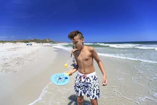 boys playing tennis on the beach