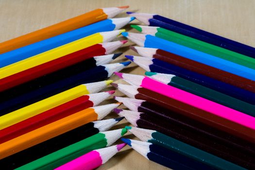 Beautiful and colorful pencil crayons. Wooden table. Black background.