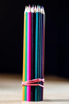 Beautiful and colorful pencil crayons. Wooden table. Black background.