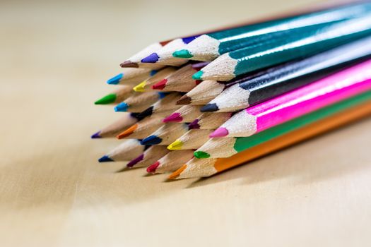 Beautiful and colorful pencil crayons. Wooden table. Black background.