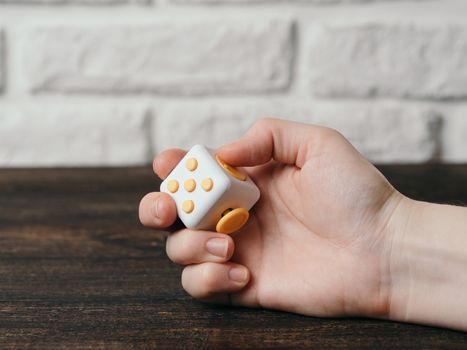 Fidget cube stress reliever in hand over brown wooden background. Fingers antistress toy in hand with copy space.