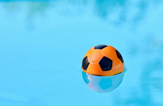 Children playing ball floating in swimming pool.