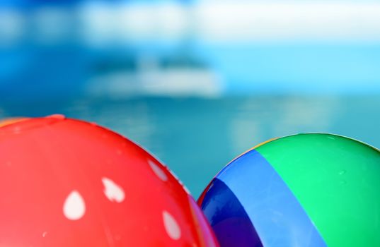 Children playing beach balls floating in swimming pool.