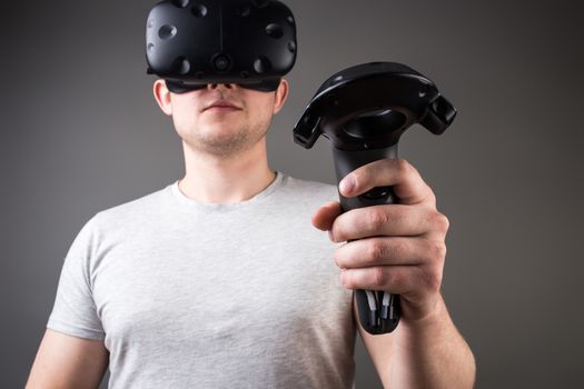 technology, gaming, entertainment and people concept - happy young man with virtual reality headset or 3d glasses with controller gamepad playing racing video game at home