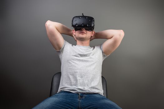 Attractive man enjoyingvirtual reality glasses in grey background.Home play concept.Smartphone use with VR goggles headset