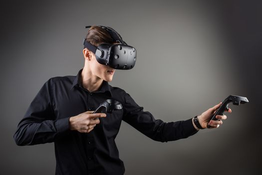 attractive man wearing virtual reality headset with two handheld trackpads or controllers