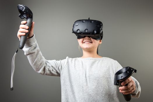 happy Cute little child girl playing game in virtual reality glasses and two joysticks