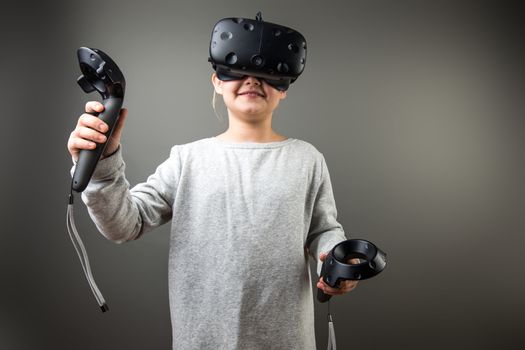 Child with virtual reality headset and joystick playing video games