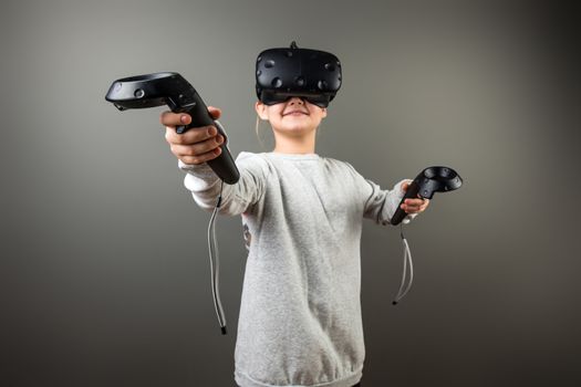 smile Child with virtual reality headset and joystick playing video games