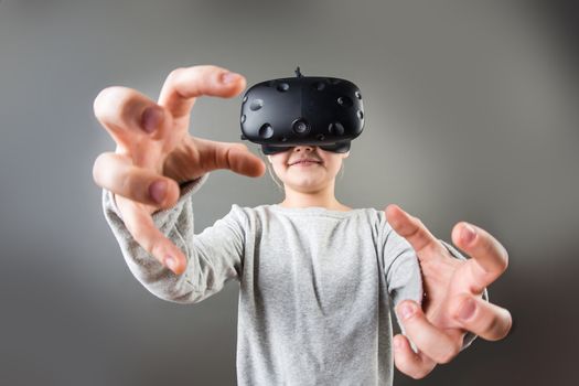 girl wearing virtual reality goggles standing on grey background. VR glasses. 360 degrees. Virtual reality headset. VR game. Wearing virtual reality goggles. Smartphone with VR. Virtual reality video.