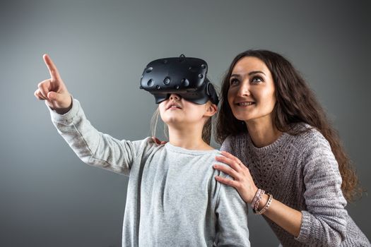 Young woman playing outdoors with cute little girl. Watching through VR device.